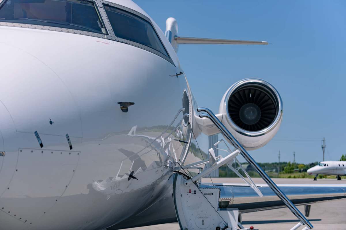 A close-up view of a private jet with a staircase and engine visible on a sunny day.