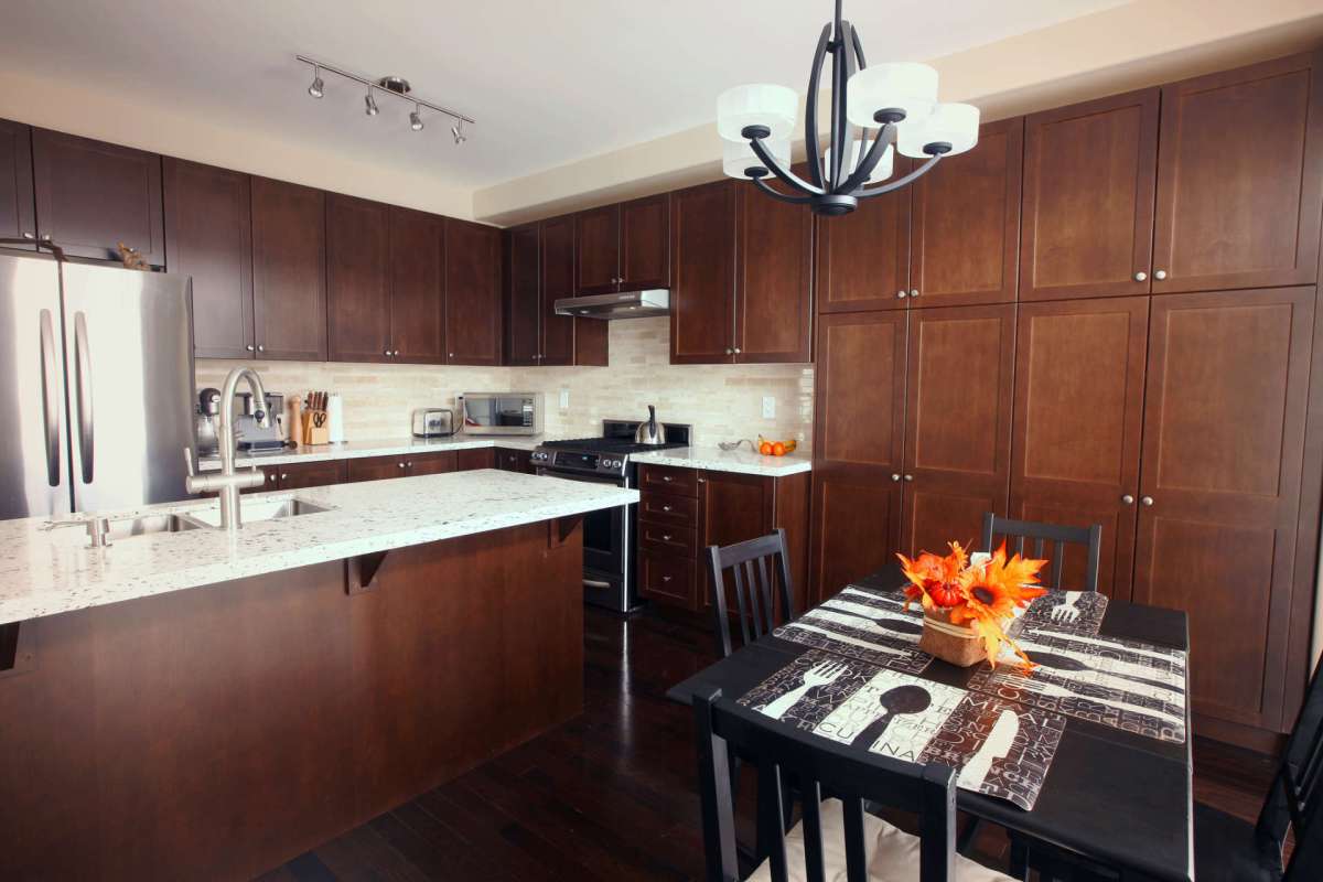A modern kitchen with dark cabinets, a marble countertop, and a dining table decorated with orange flowers.