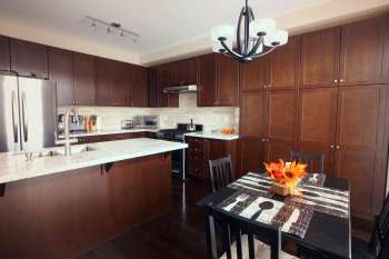 A modern kitchen with dark cabinets, a marble countertop, and a dining table decorated with orange flowers.