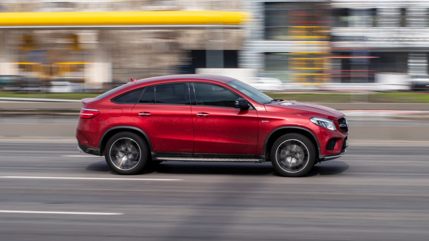 A red car drives past on a city street.