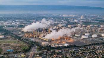 An industrial area with oil refineries, storage tanks, and smoke emissions.