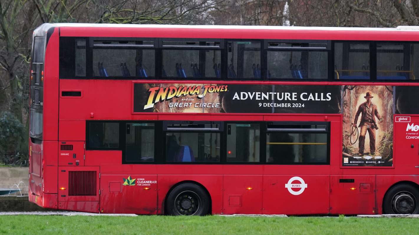 A red double-decker bus with an advertisement for "Indiana Jones and the Great Circle."