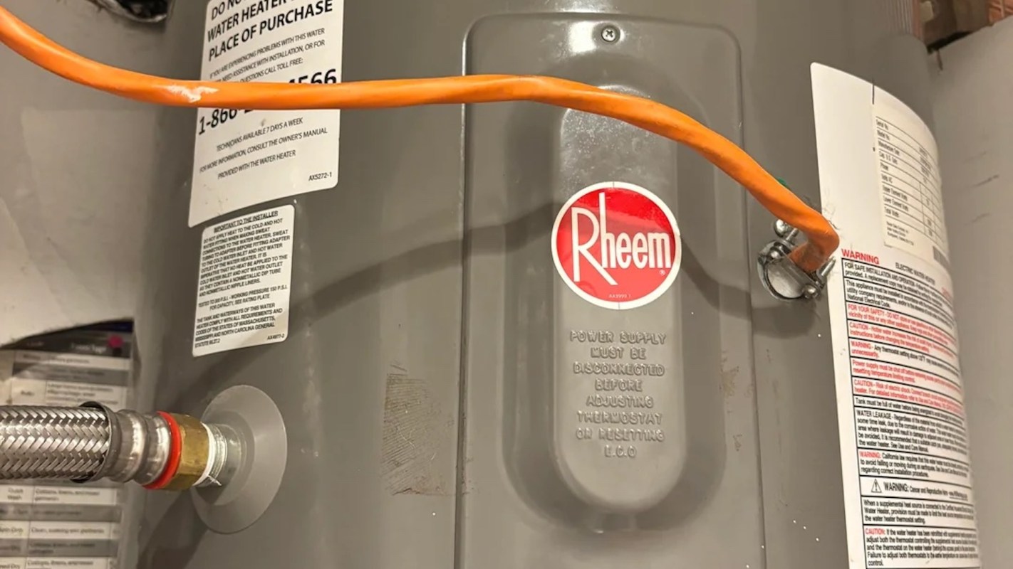 A Rheem water heater with a power supply cord and warning labels.