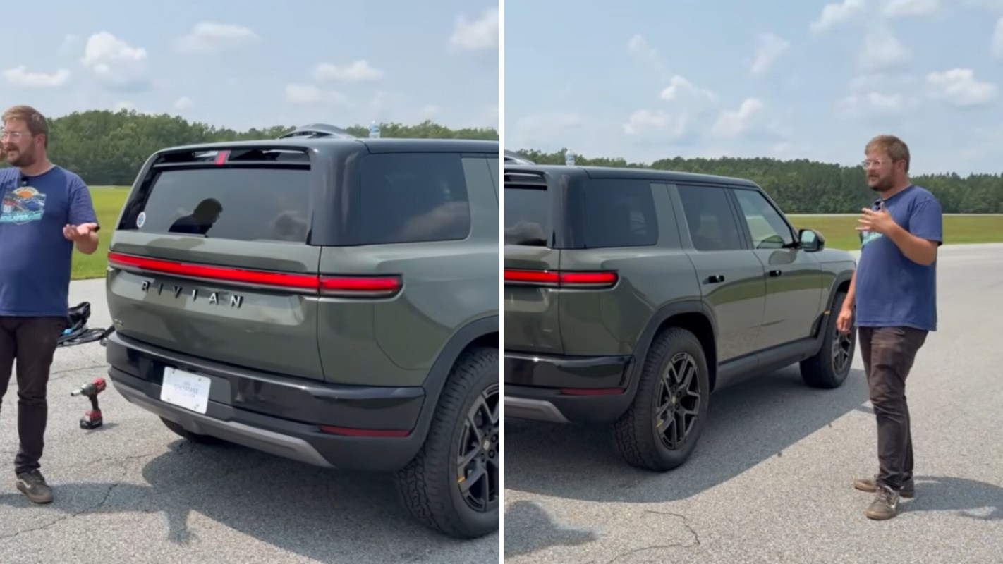 A person stands next to a green Rivian SUV on a paved area with trees in the background.