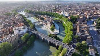 An aerial view of a city with rivers, bridges, and greenery among buildings.