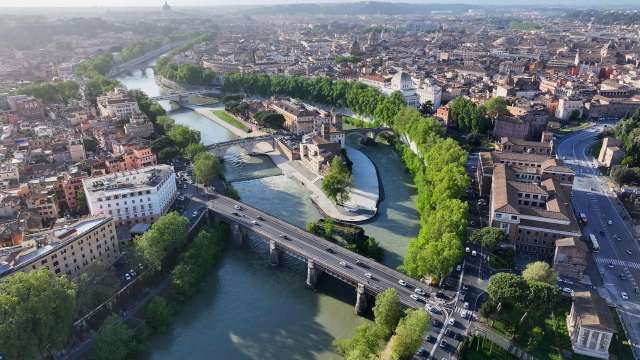 An aerial view of a city with rivers, bridges, and greenery among buildings.