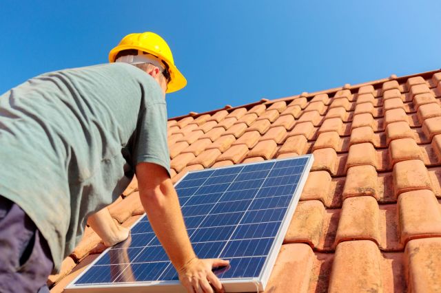 A technician adding solar panels to a roof.