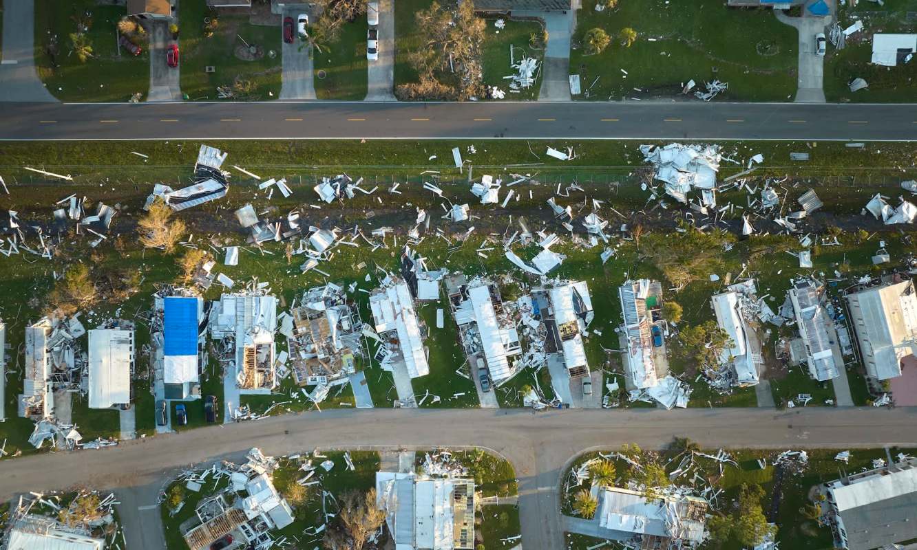 An aerial view of a neighborhood showing damaged houses and scattered debris.