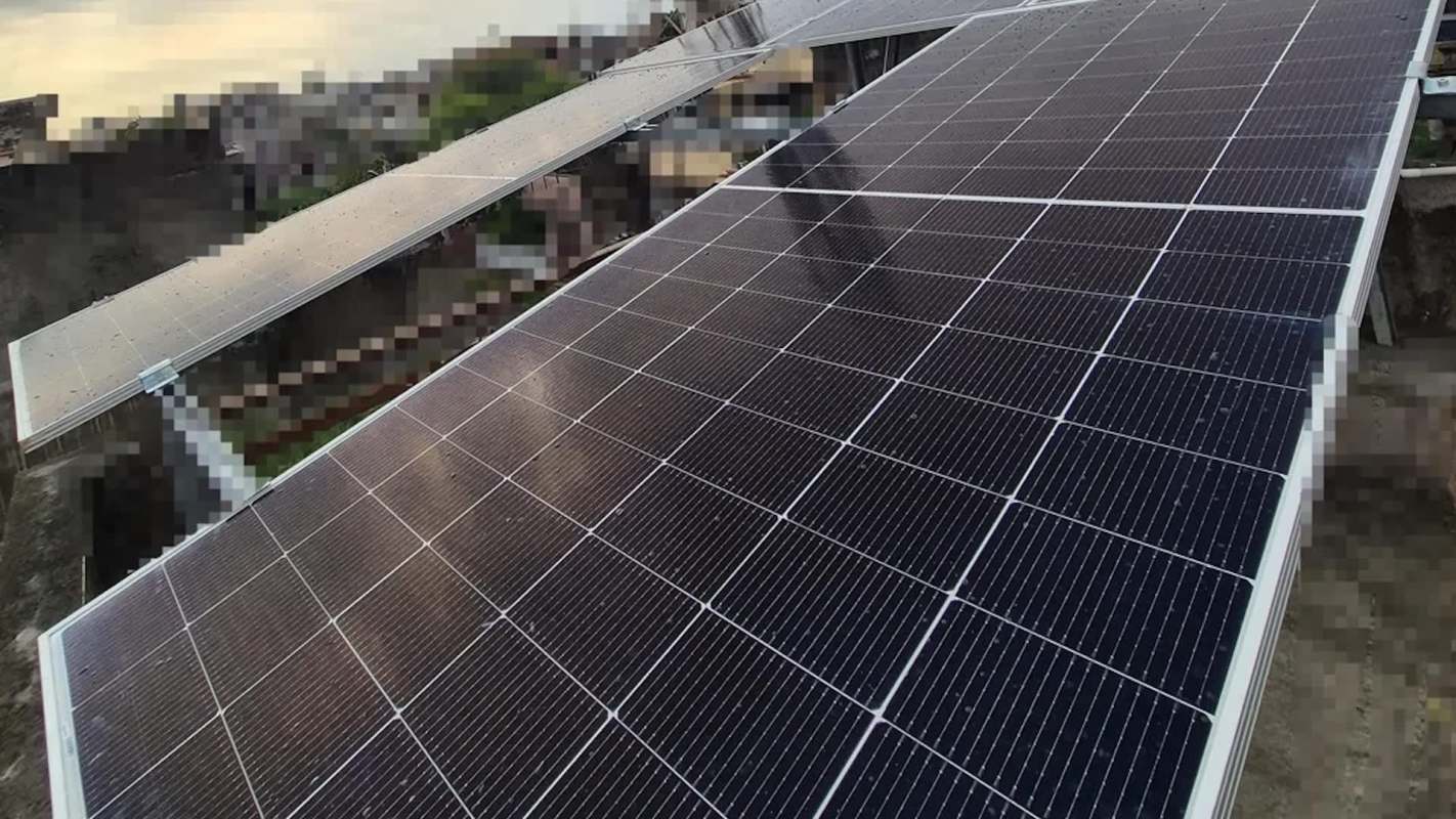 Solar panels installed on a rooftop with a cityscape in the background.