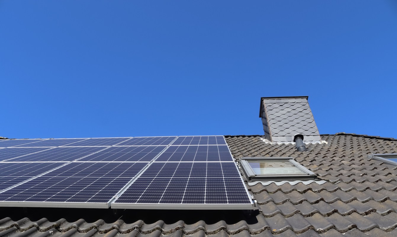 Solar panels installed on a roof under a clear blue sky.