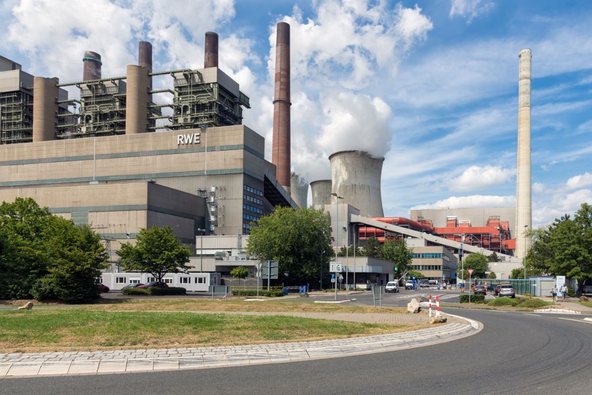 A RWE power plant with cooling towers and multiple chimneys under a blue sky with scattered clouds.