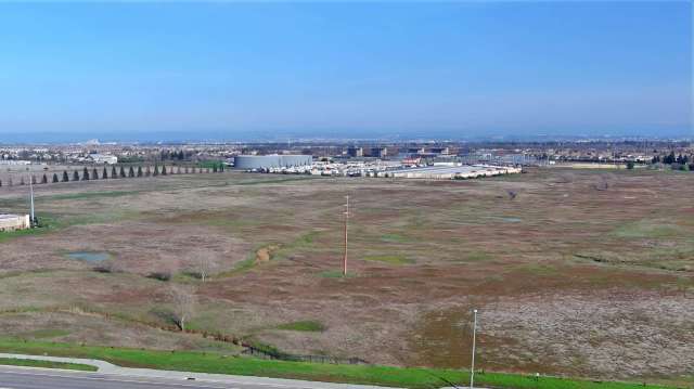 An undeveloped field near industrial buildings.