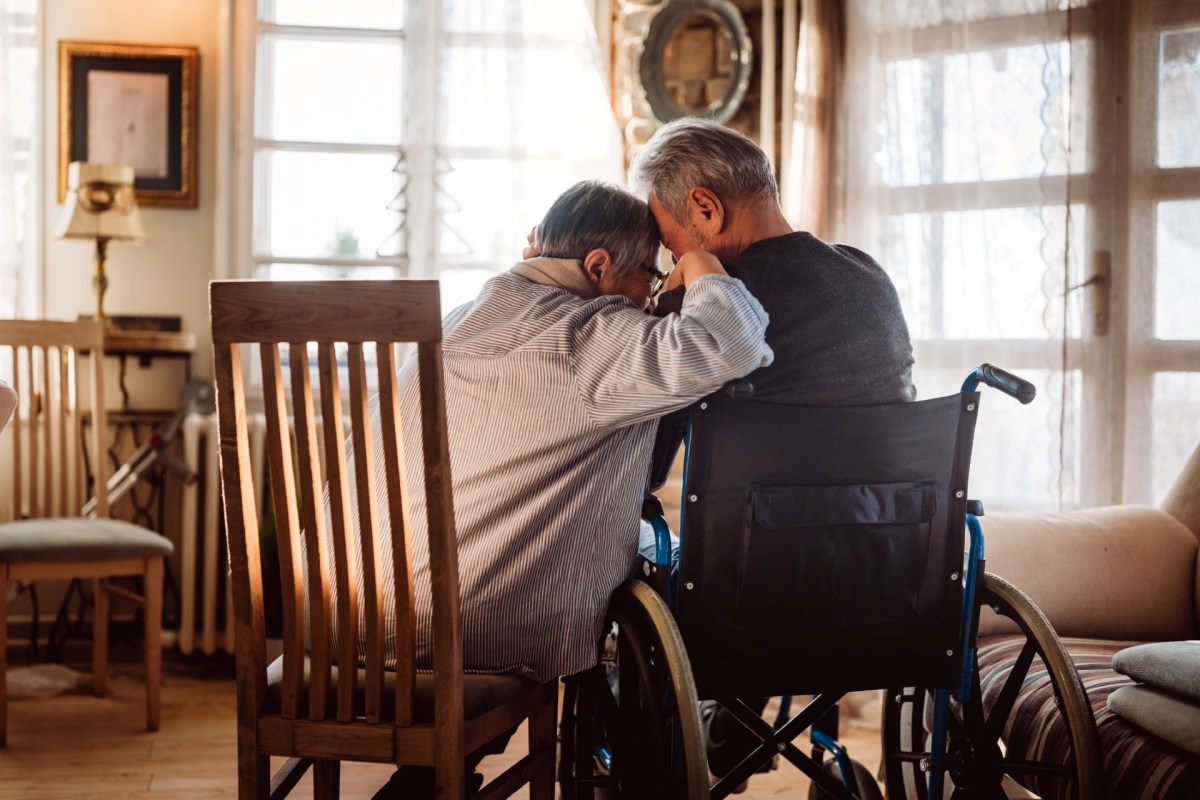 A senior couple lean on each other.