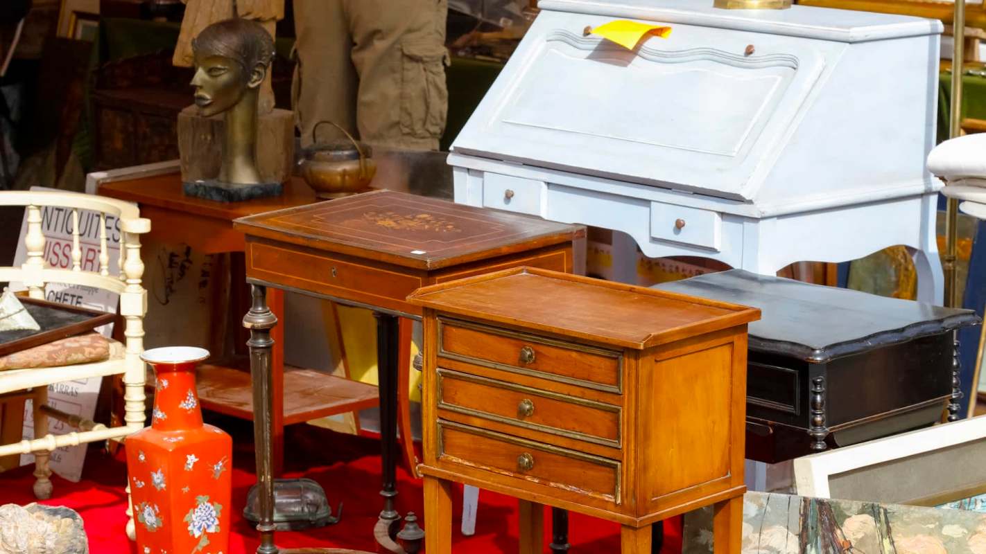 Various antique furniture pieces including tables, a vase, and a decorative bust on display.