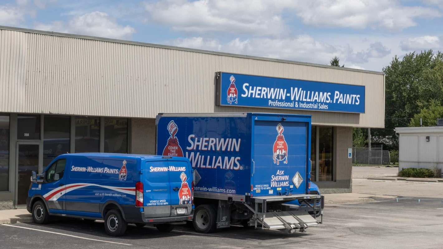 A Sherwin-Williams store with a blue delivery truck and van parked in front.