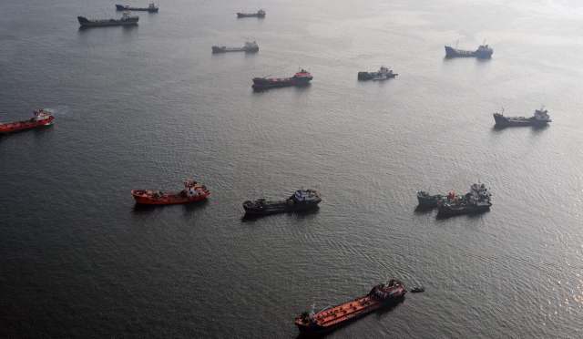 Several boats are anchored on calm water.