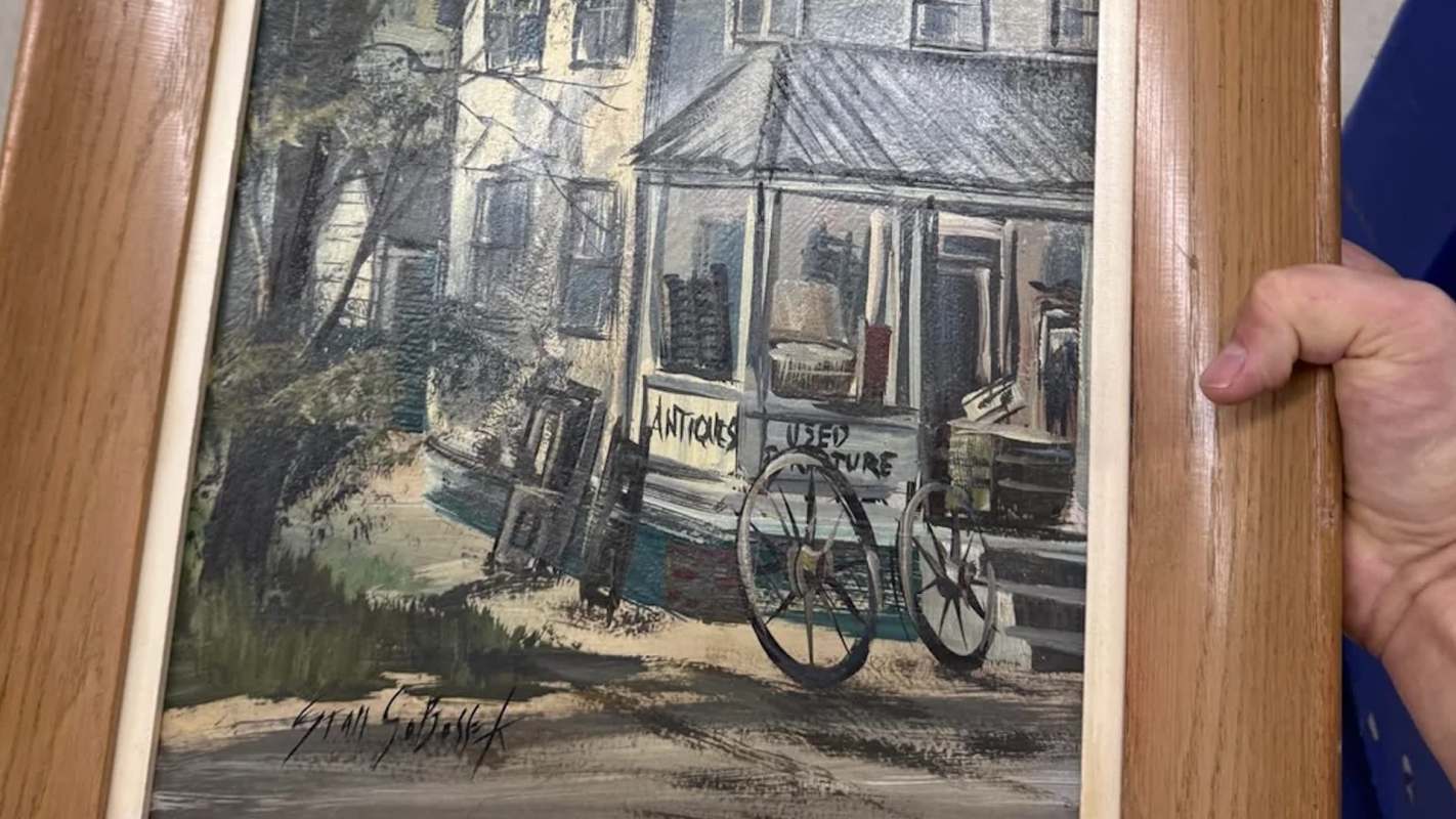 A bicycle near an antique shop with a sign reading "Antiques Used Furniture" and surrounding trees.