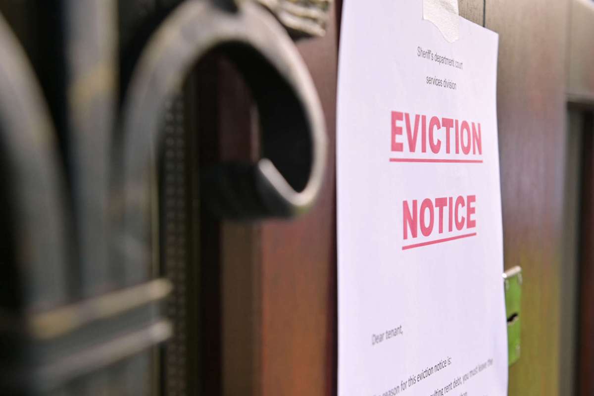 An eviction notice is posted on a door, detailing the notice to the tenant.