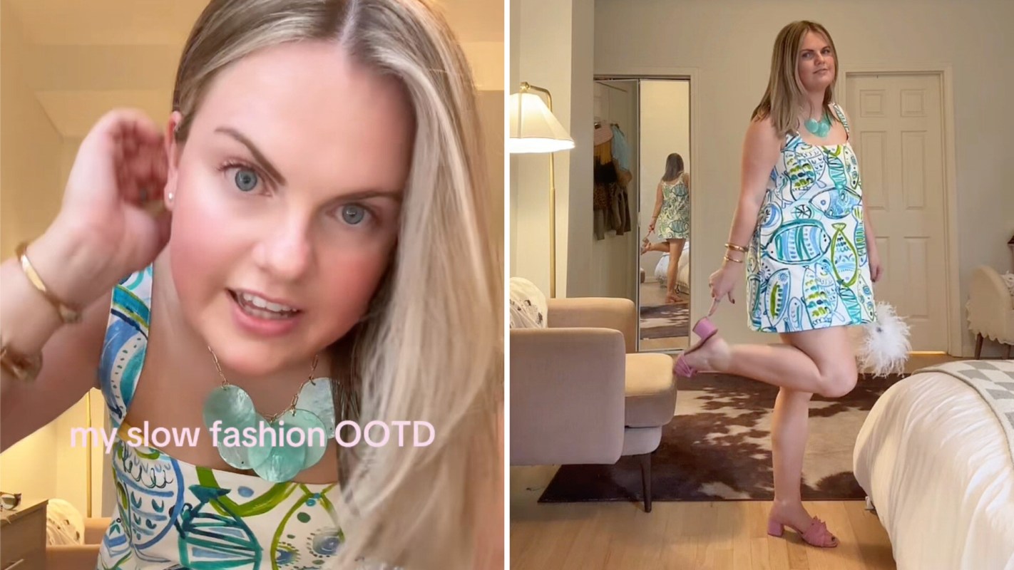 A woman models a colorful dress with fish patterns in a stylish room with a mirror and a bed.