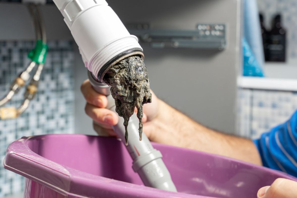 A person unclogging a sink pipe.