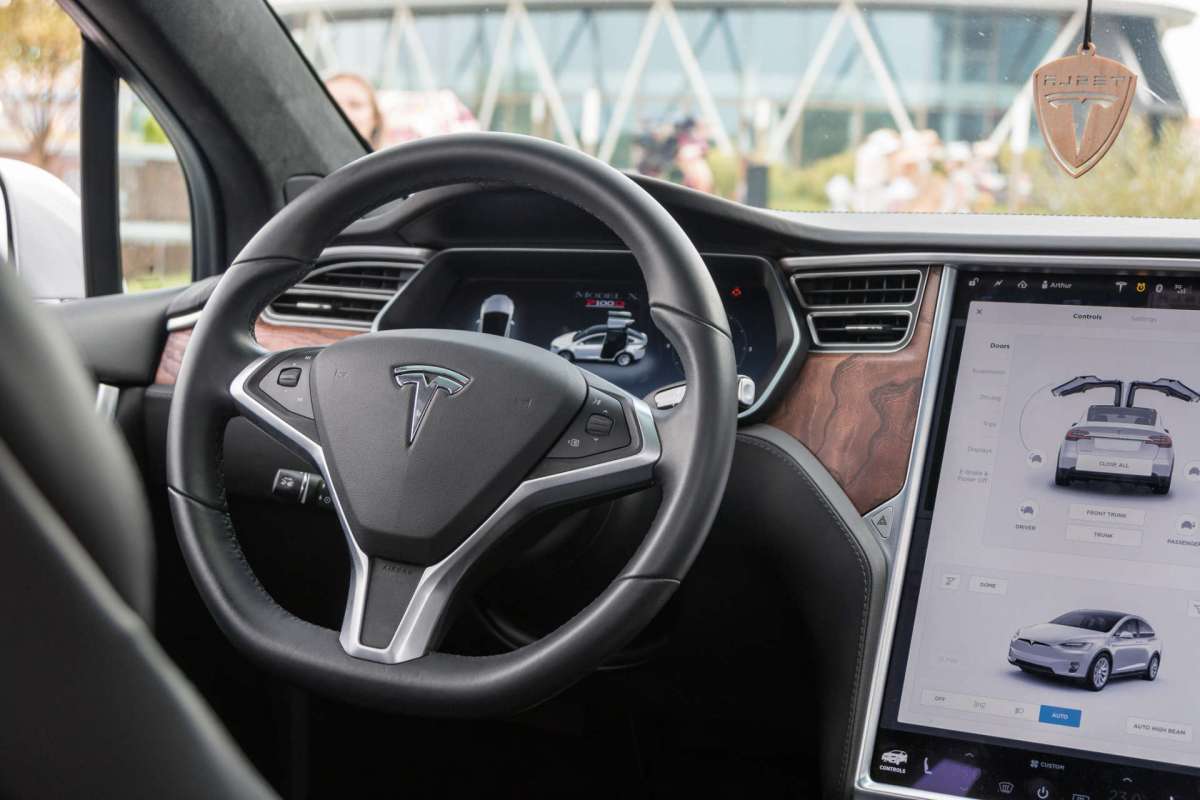 The interior of a Tesla car featuring a steering wheel, dashboard display, and control interface.