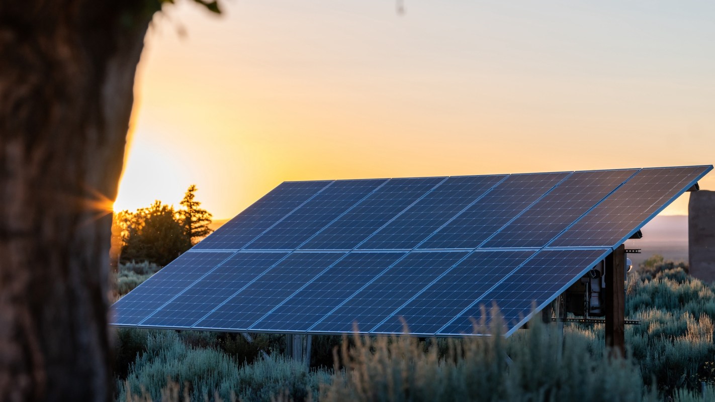 A solar panel system in a field at sunset.