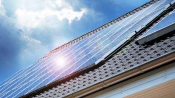 Solar panels installed on a sloped roof under a cloudy sky.