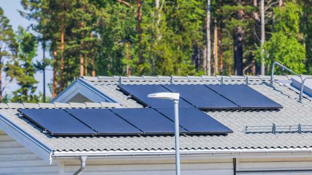 Solar panels installed on a roof with trees in the background.