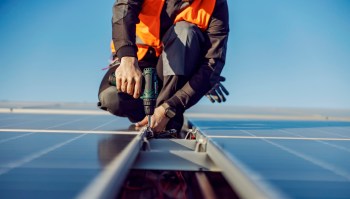 A technician securing a rooftop solar panel.