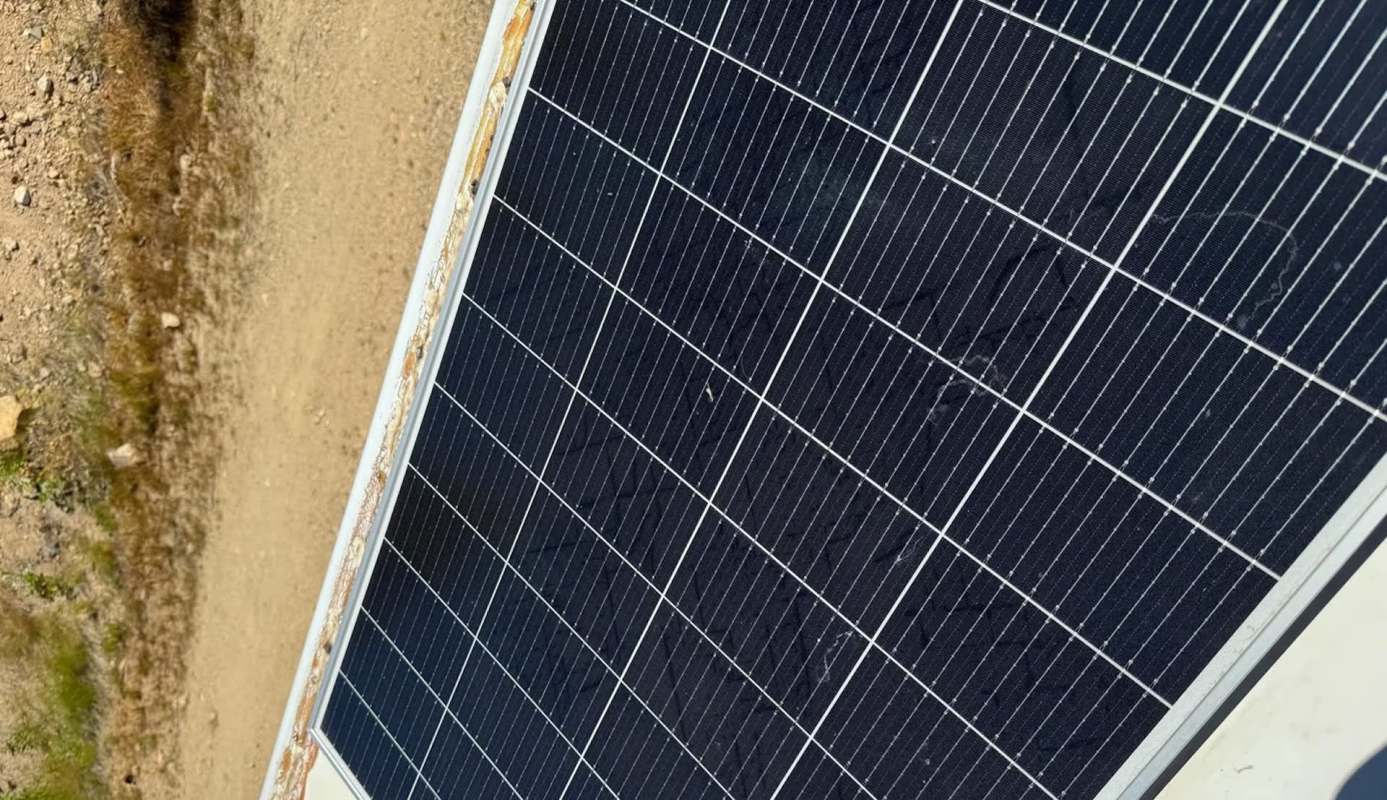 A solar panel positioned on a sandy surface.