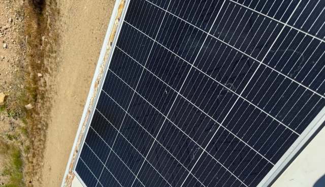 A solar panel positioned on a sandy surface.