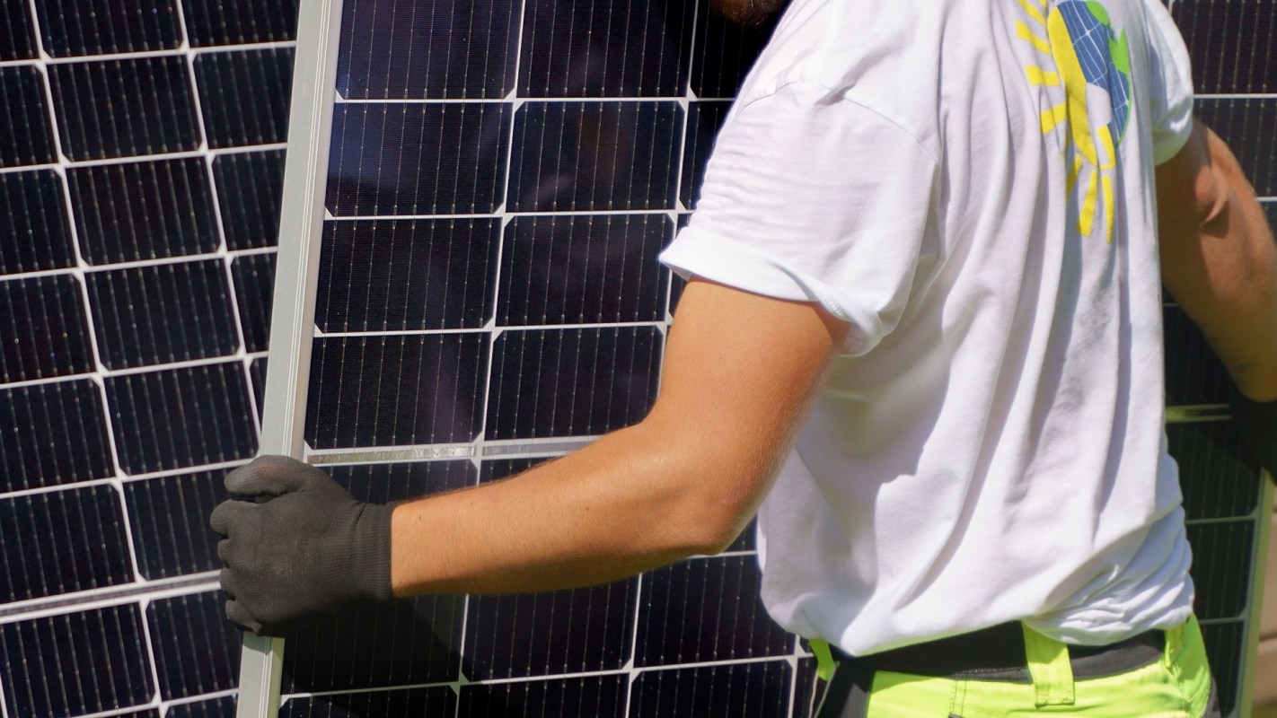 A worker in gloves stacking solar panels.