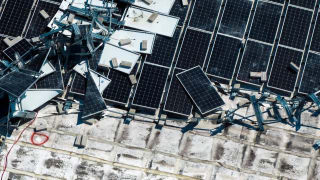 Damaged solar panels and frames scattered on a rooftop.