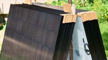 Stacked solar panels with cardboard edge protectors.