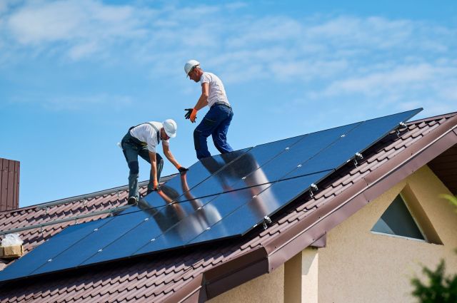 Workers installing solar panels on a roof.