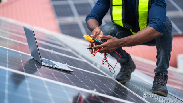 A technician checking rooftop solar panels.
