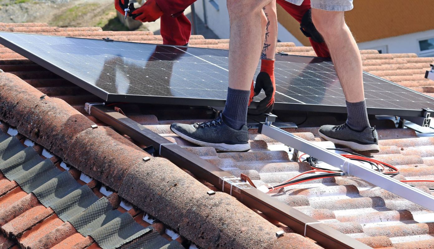 Two people installing a solar panel.