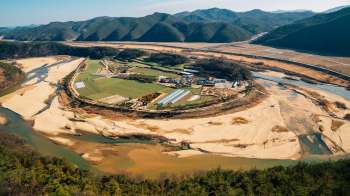 Aerial view of a river winding through agricultural land and hills in a dry rural landscape.