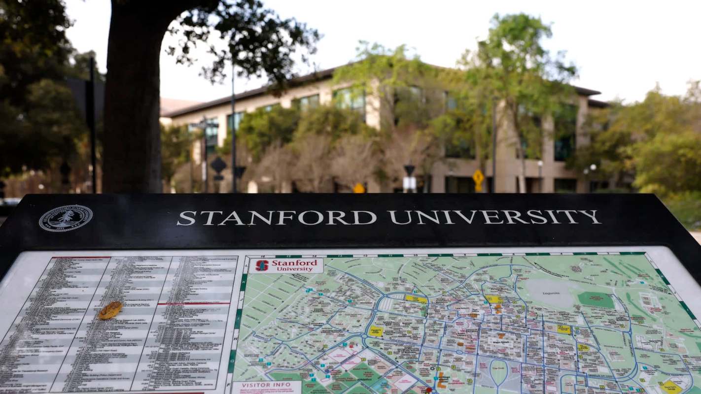 A campus map displaying Stanford University with directional information and a nearby building in the background.