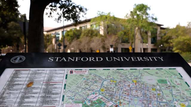 A campus map displaying Stanford University with directional information and a nearby building in the background.