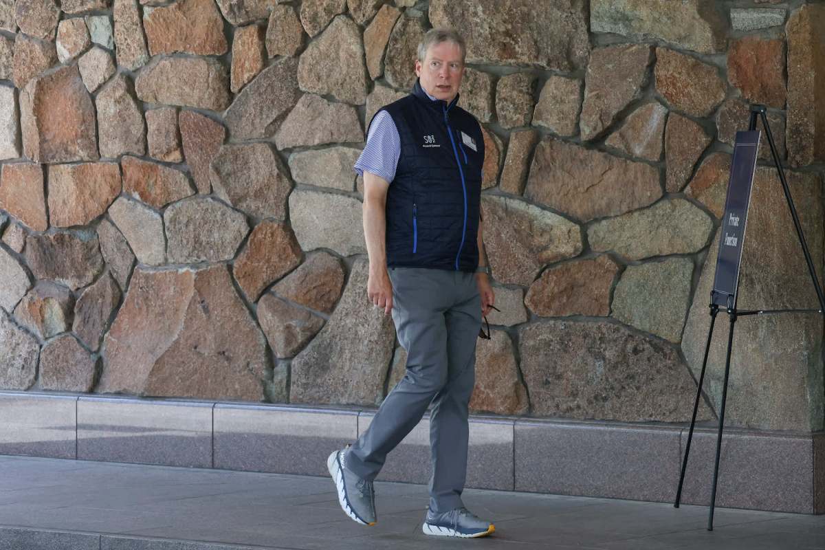 A man wearing a vest and gray pants walks beside a stone wall and a sign that reads "Private Function."