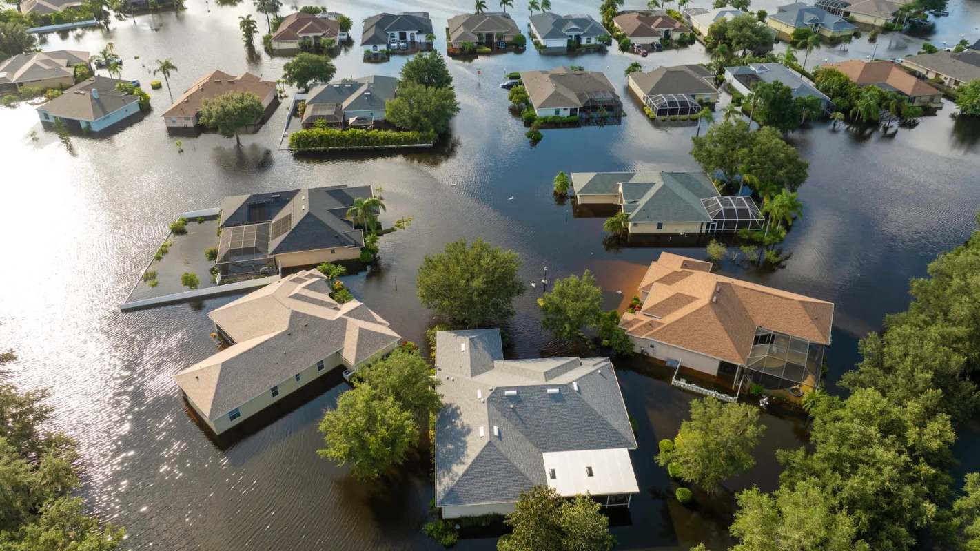 Aerial view of residential homes partially submerged in floodwaters.