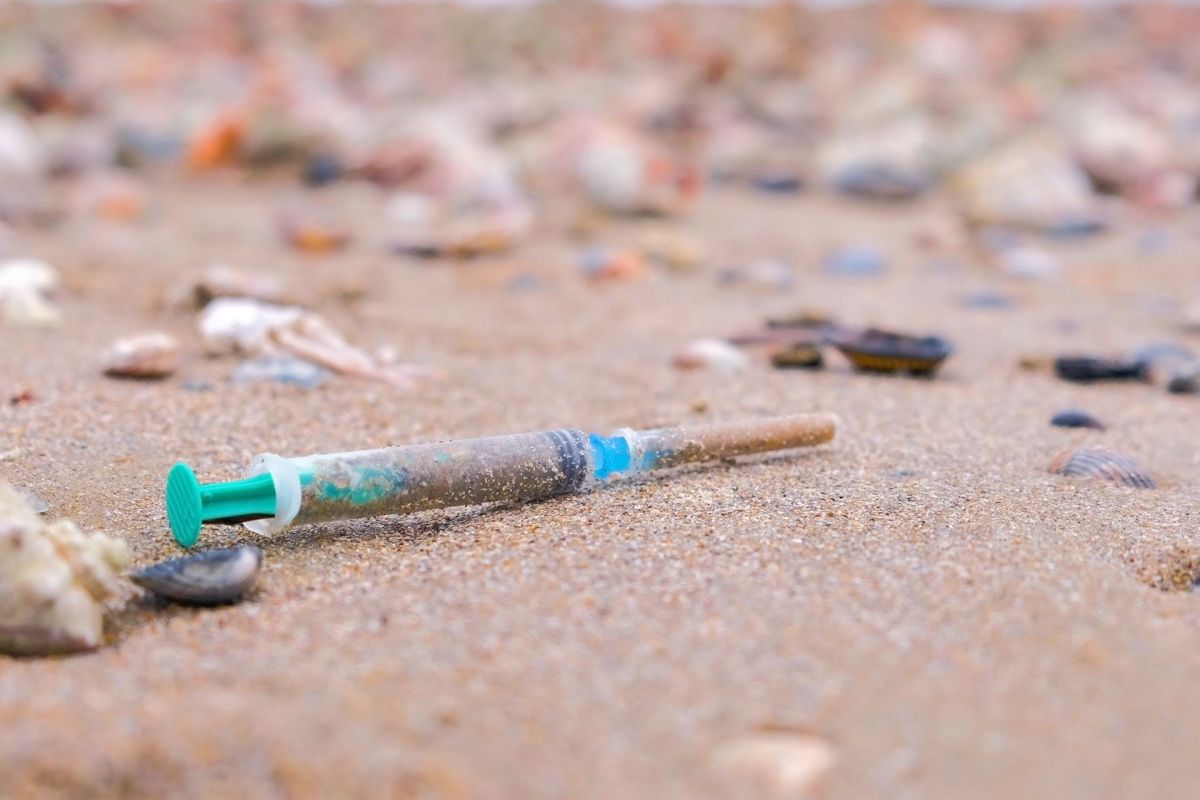 A syringe on a beach.