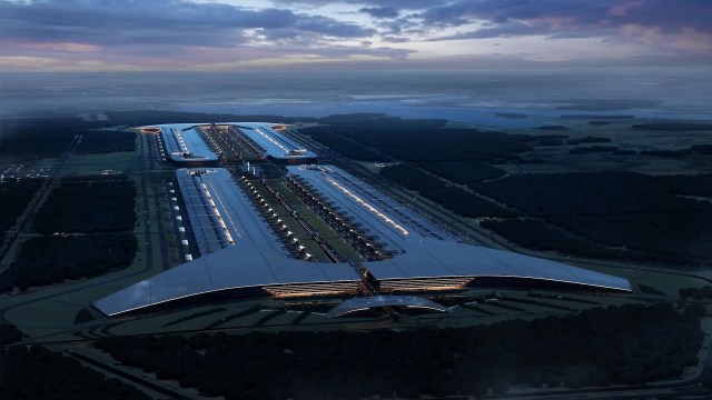 Aerial view of a large, modern building complex surrounded by greenery at dusk.