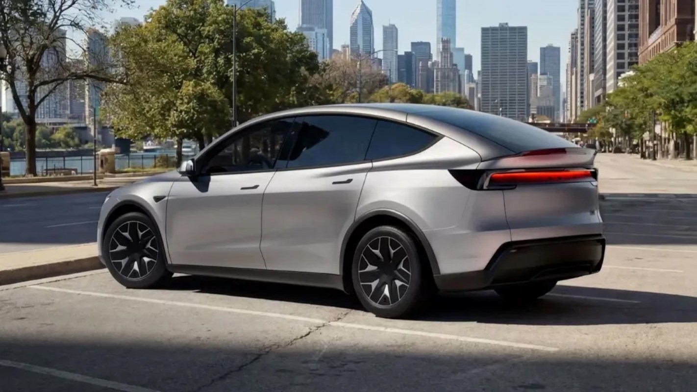 A silver electric car parked on a street with a city skyline in the background.