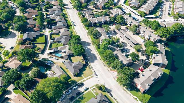 An aerial view of a suburban neighborhood with houses, trees, and a street.