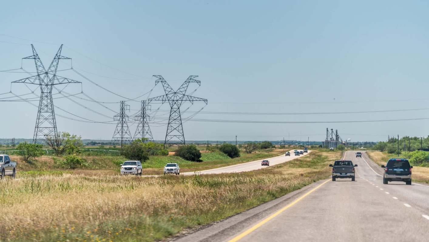 A highway with several cars and power lines in the background.