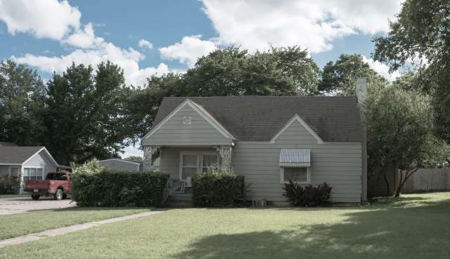 A single-story house with a front porch and a red truck parked nearby.