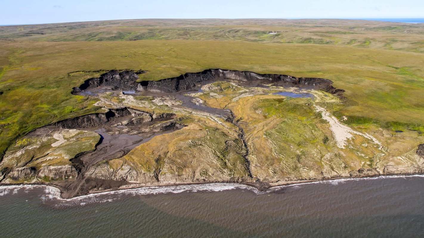 An aerial view of a coastal landscape with eroded cliffs.