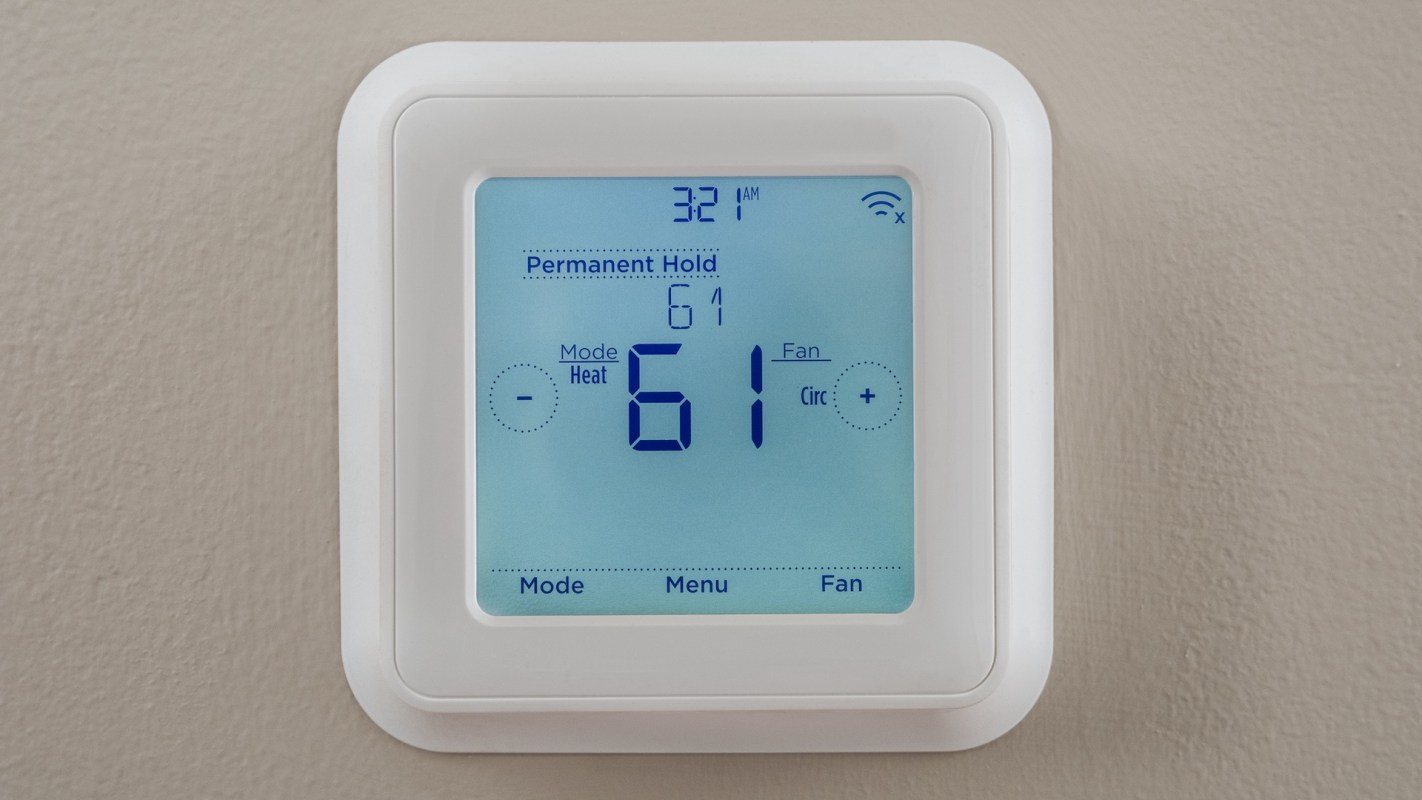 A digital thermostat displaying a temperature of 61°F and mode settings.